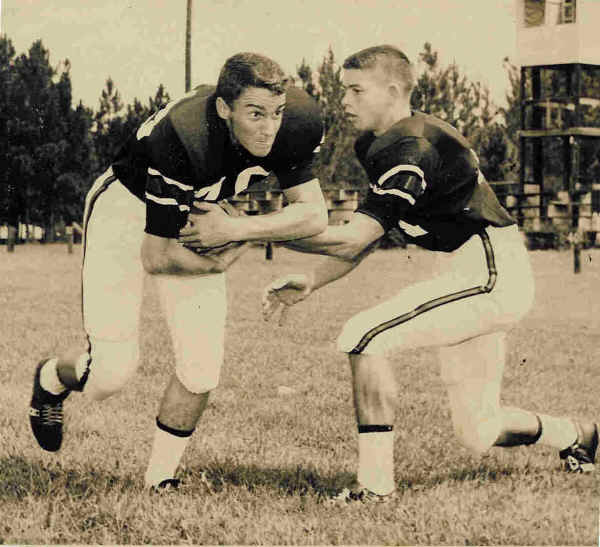 Two uniformed football players posed with a ball, from the Class of ’64 archive.